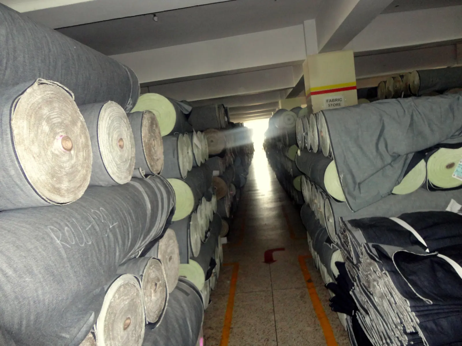 Rolls of denim fabric stored on racks in a garment factory fabric store