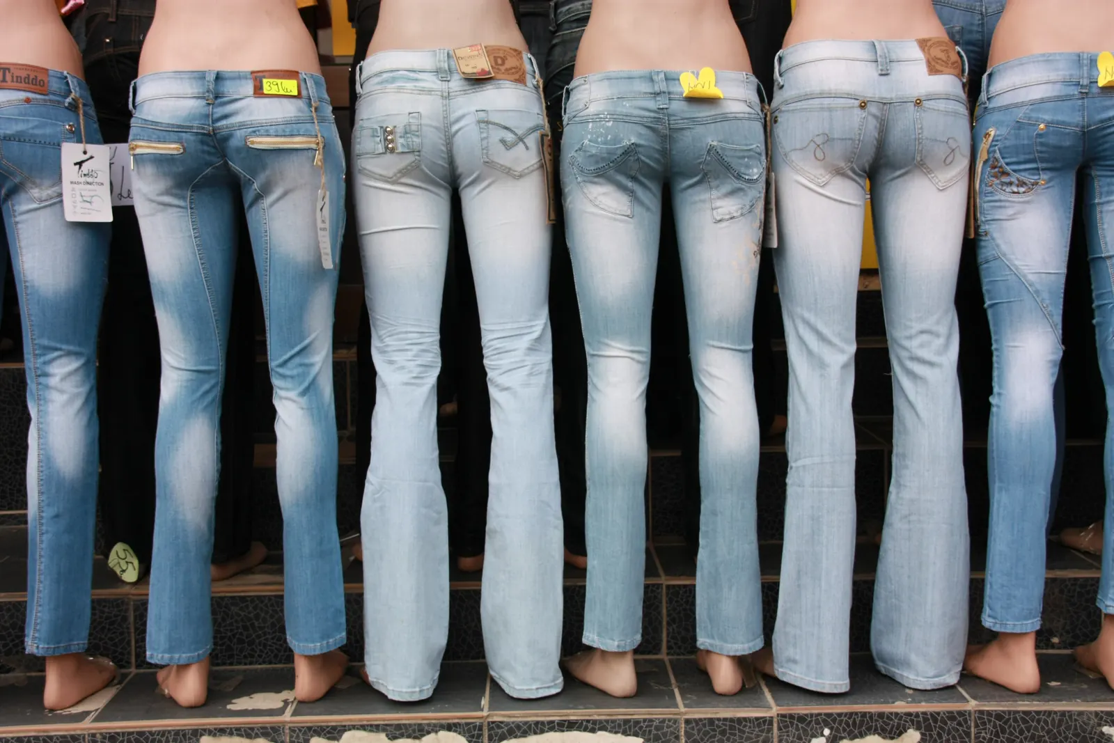 A row of jeans on display mannequins, each a visibly different shade of blue