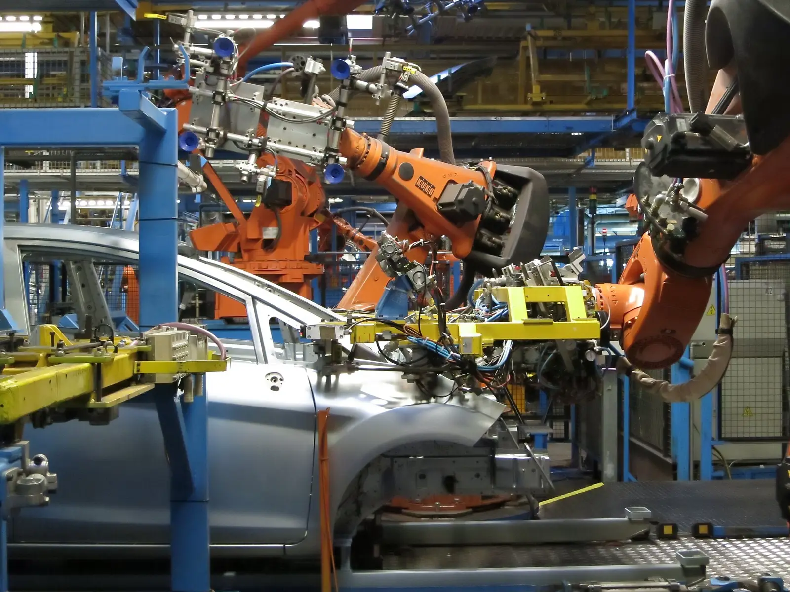 Robots working on car bodies along an automotive assembly line