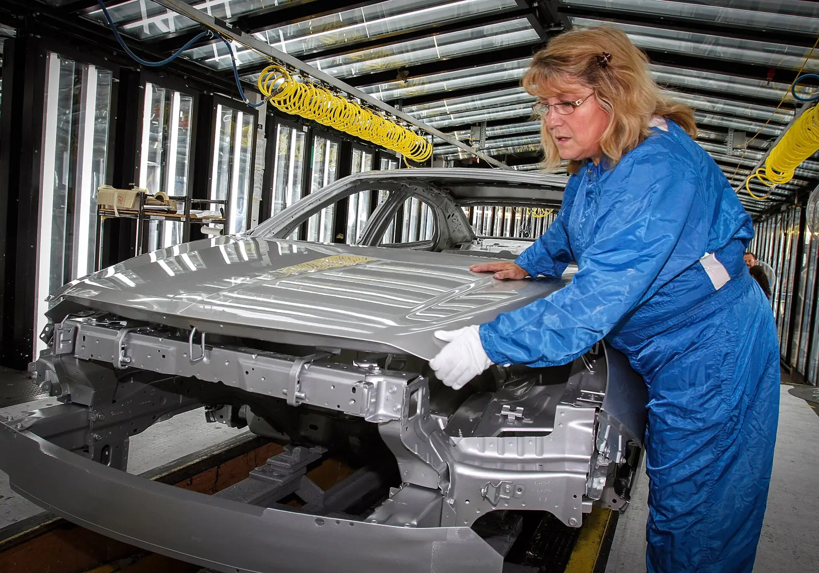 Worker inspecting a car body on an automotive assembly line