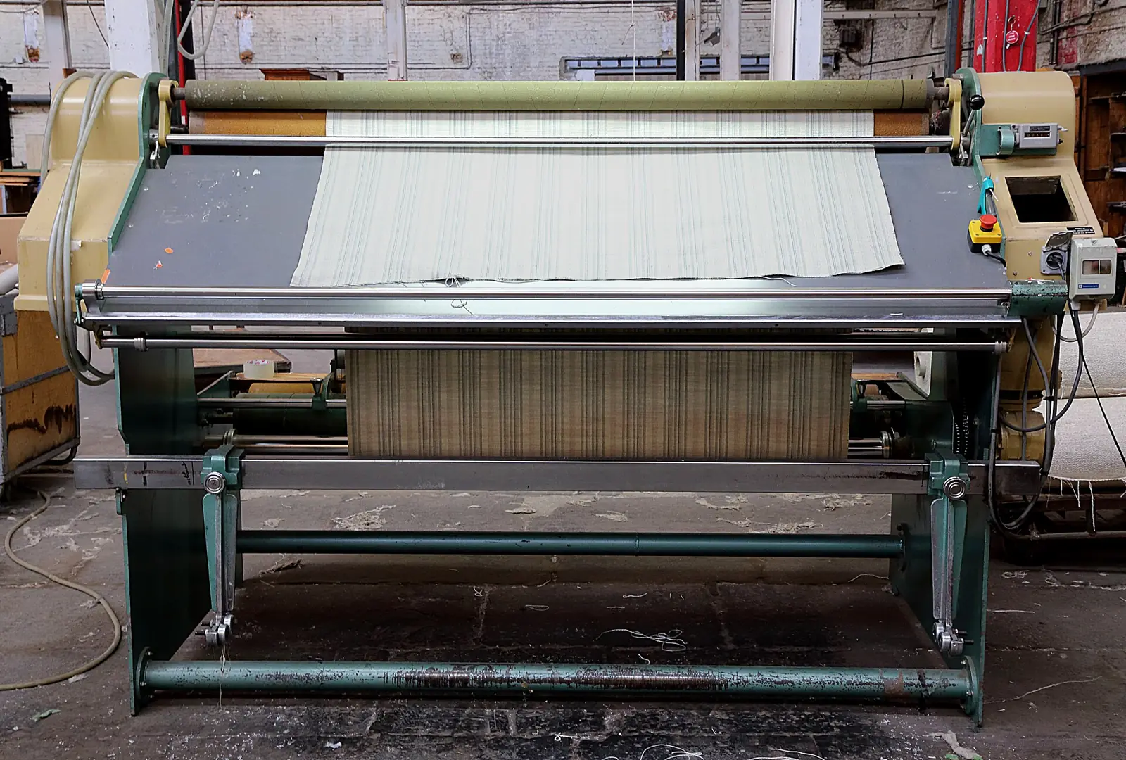 Fabric inspection machine with a roll of fabric running over the inspection table
