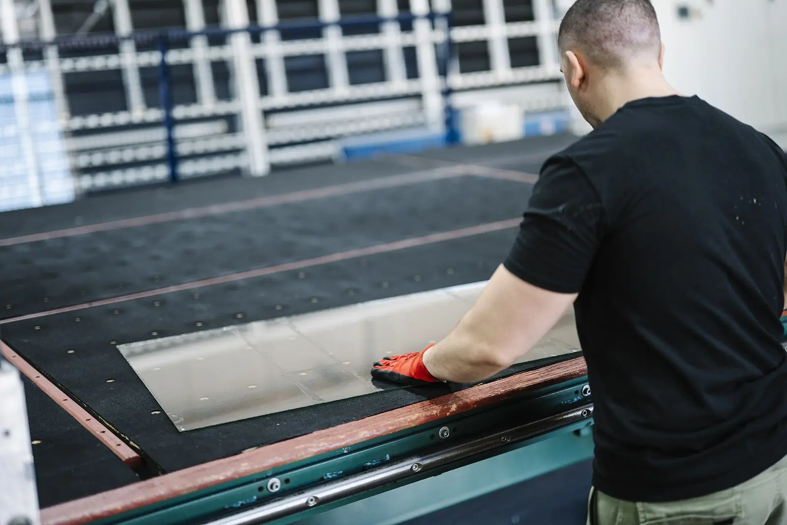 Worker handling a metal sheet on a production table