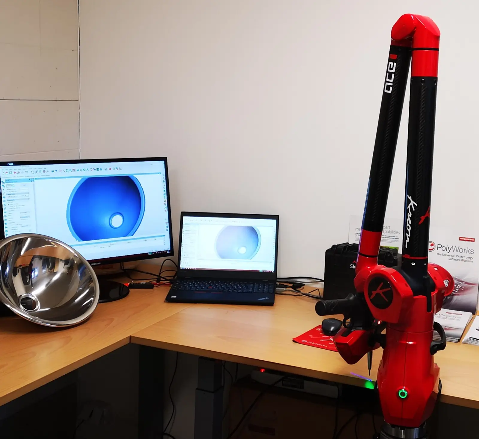 Portable measuring arm next to a computer showing a scanned part