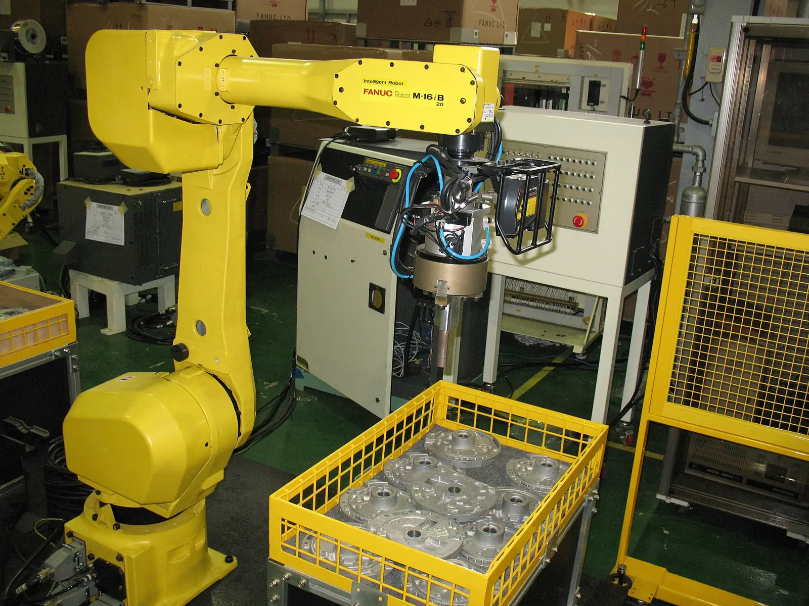 Industrial robot picking parts from a crate inside a safety cell