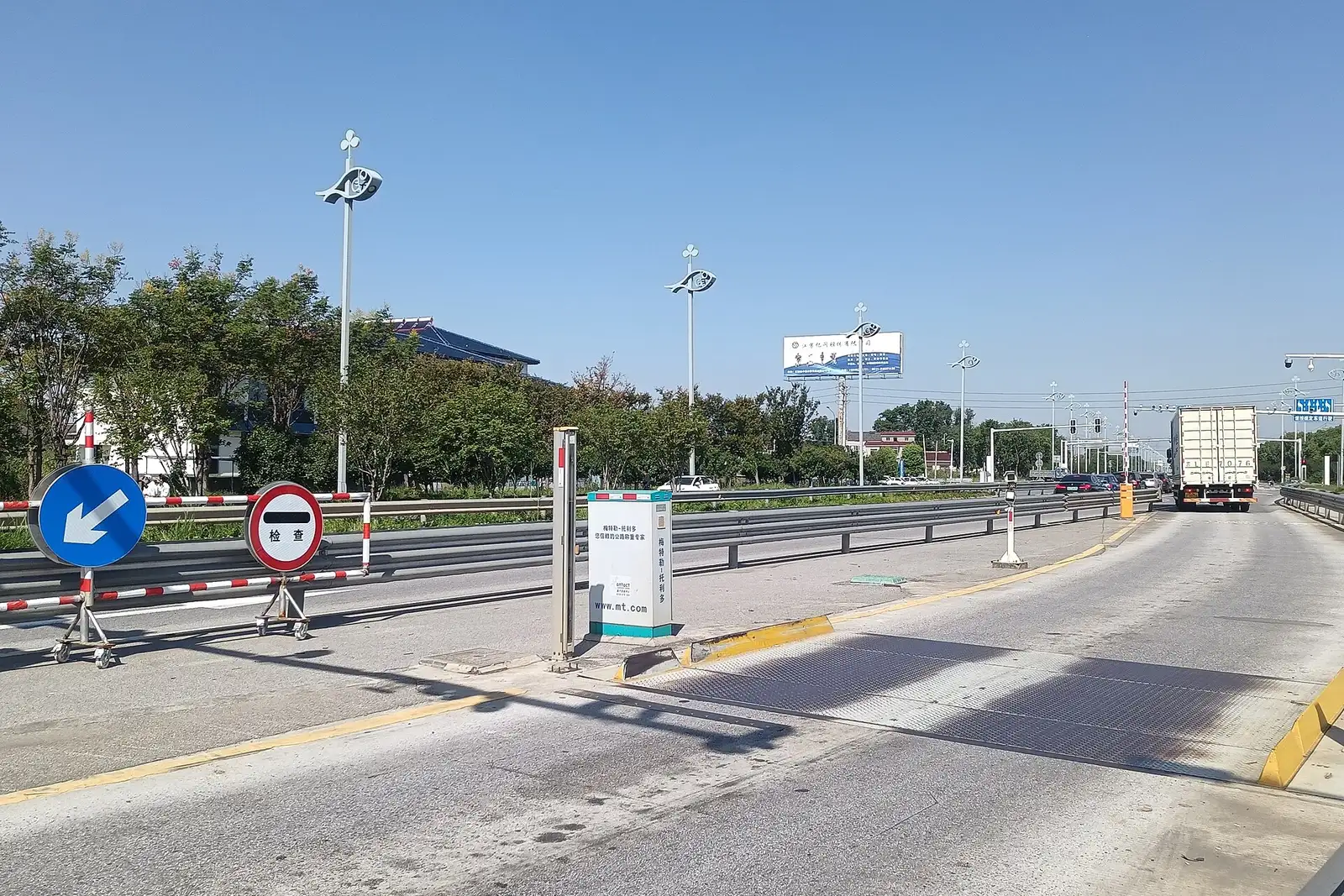 Truck weighbridge lanes with a barrier and lane signs at a freight entrance